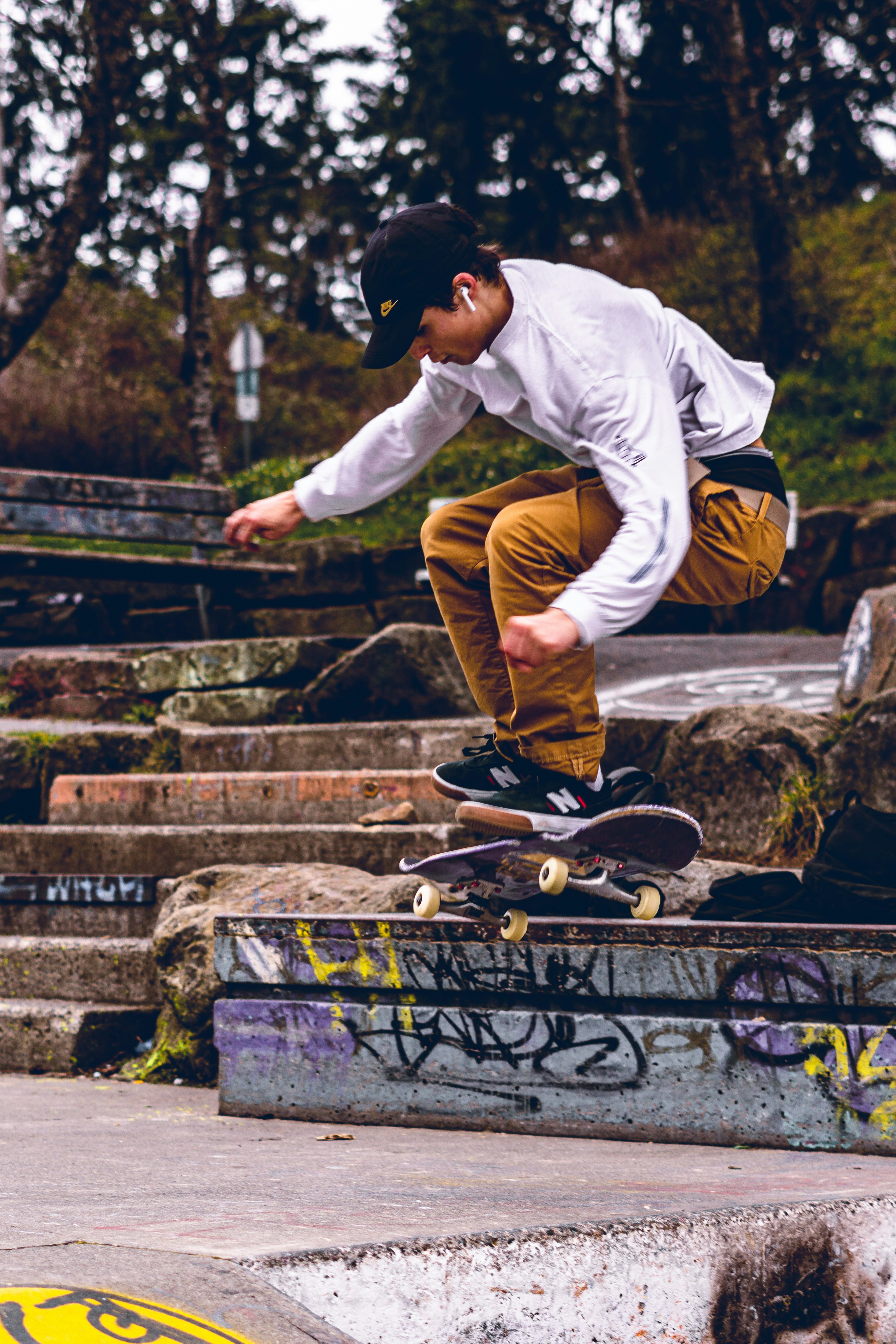 man in white long sleeve shirt and brown pants sitting on black metal fence during daytime